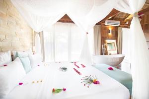 a bedroom with a white bed with flowers on it at Tulia Zanzibar Unique Beach Resort in Pongwe