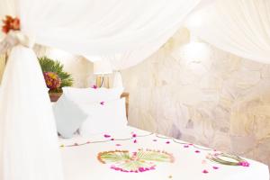 a bed with a white canopy with flowers on it at Tulia Zanzibar Unique Beach Resort in Pongwe