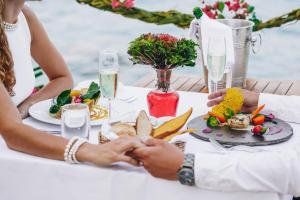 a couple holding hands at a table with food at Tulia Zanzibar Unique Beach Resort in Pongwe