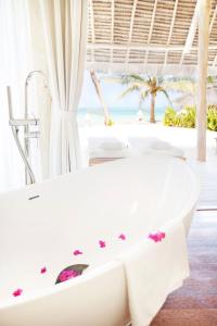 a bathroom with a white tub and a beach at Tulia Zanzibar Unique Beach Resort in Pongwe