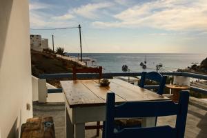 a wooden table and chairs on a balcony overlooking the ocean at Perigiali Rooms & Apartments Folegandros in Agali