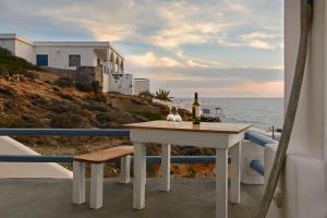 a table with a bottle of wine on a balcony overlooking the ocean at Perigiali Rooms & Apartments Folegandros in Agali