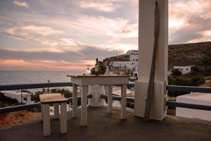 a table with a bottle of wine on a balcony with the ocean at Perigiali Rooms & Apartments Folegandros in Agali