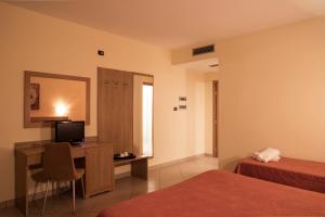 a hotel room with two beds and a desk with a television at Manhattan Village Hotel in Sulmona