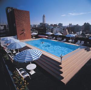 a swimming pool with a blue umbrella on top of it at Hotel Royal-Nikko Taipei in Taipei