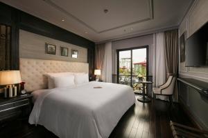 a bedroom with a large white bed and a balcony at La Sinfonía Citadel Hotel and Spa in Hanoi