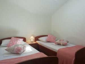Habitación con 2 camas y almohadas rosas y blancas. en Apartments Vidović, en Vodice