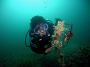 un hombre con traje de buceo y gafas mirando una planta en Camiguin Volcan Beach Eco Retreat & Dive Resort, en Mambajao