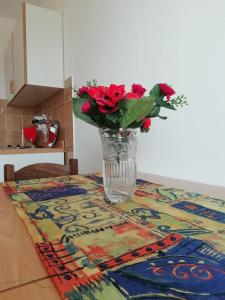 un jarrón lleno de rosas rojas sentadas en una mesa en Apartments Vidović, en Vodice
