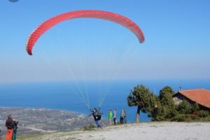 a person flying a parachute on top of a hill at Agkaze in Palaios Panteleimonas