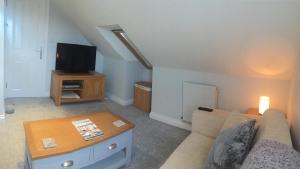 Una sala de estar con un sofá y un televisor. en Rosenn Teyr, en St. Agnes