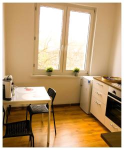 a kitchen with a table and chairs and two windows at Apartament Katarzynka Stare Miasto in Toruń