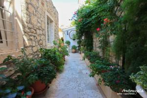 an alley with flowers and plants in an old building at Apartment & Rooms Antonijela in Bol