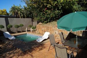 Johannesburg的住宿－威斯特摩蘭山林小屋，一个带桌椅和遮阳伞的游泳池