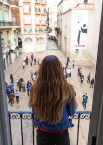 Una mujer mirando por una ventana en una calle de la ciudad en Loft Pasarela en Alicante