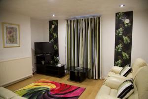 a living room with two couches and a television at La Suisse Serviced Apartments in Manchester