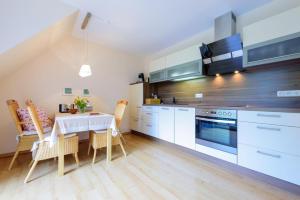 a kitchen with white cabinets and a table with chairs at Arielle Nr 6 - für die schönste Zeit des Jahres - all inclusive - Wäschepaket - PowerWLAN - eigene Fahrradbox mit Stromanschluss und eigener kostenfreier Parkplatz in Zingst