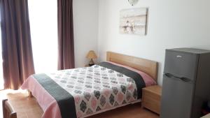 a small bedroom with a bed and a refrigerator at Apartmani Luna in Novalja