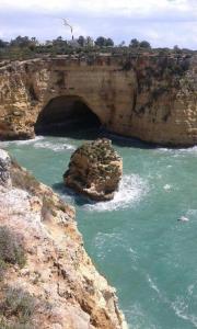 a cave in a rock in the middle of the water at Apartamentos - Solar Vale Covo in Carvoeiro