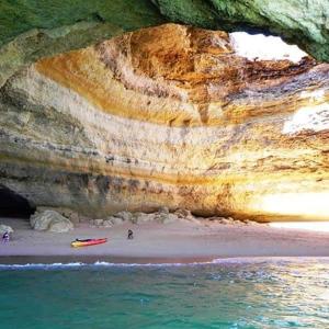 a beach with a boat on the sand and water at Apartamentos - Solar Vale Covo in Carvoeiro