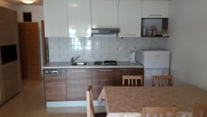 a kitchen with a table and a sink and a refrigerator at Apartmani Luna in Novalja