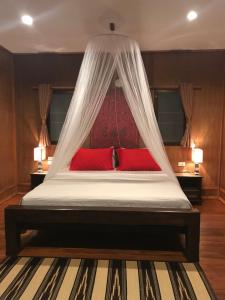 a bedroom with a bed with red pillows and a canopy at Thai Terrace Bungalow in Thong Nai Pan Yai