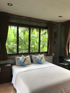 a bedroom with a large white bed with windows at Thai Terrace Bungalow in Thong Nai Pan Yai
