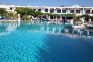a large pool of blue water in front of a hotel at Garden Hotel in Pastida
