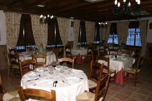 un comedor con mesas y sillas blancas y ventanas en Hostal Mesón La Era, en Ríogordo