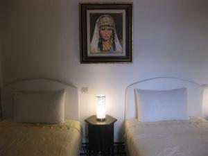 a bedroom with two beds and a painting on the wall at Riad Sabah in Fez