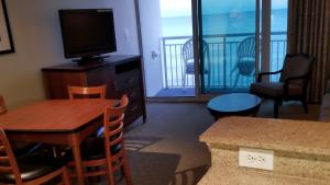 ein Wohnzimmer mit einem TV, einem Tisch und Stühlen in der Unterkunft Direct Ocean Front 8th Floor in Myrtle Beach