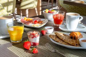 - une table avec des assiettes de produits pour le petit-déjeuner et des boissons dans l'établissement Hôtel Ginkgo - SPA Biloba, à Quimper