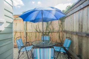 een glazen tafel met twee stoelen en een blauwe paraplu bij Crescent City Cottage in New Orleans