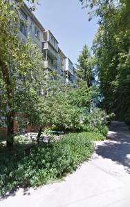 a building on a street with trees and a sidewalk at Apartment near city center on Peremohy Avenue 46 in Chernihiv