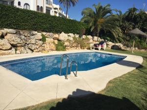 einen Pool in einem Garten mit einer Felswand in der Unterkunft BALCON DEL MAR 2-3 A, APARTAMENT ON THE BEACH FRONT in La Cala de Mijas