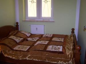 a bedroom with a bed with a blanket and two windows at Wakacje Kołobrzeg EU in Kołobrzeg