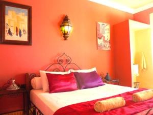 - une chambre rouge avec un lit doté d'oreillers rouges et violets dans l'établissement L'Arganier Solitaire, à Souira Guedima