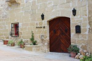 um edifício de pedra com uma porta de madeira e algumas plantas em Molendini em Għarb