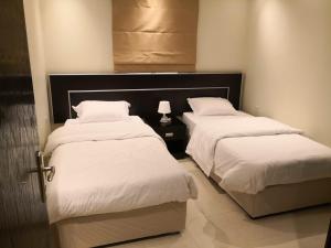 two beds with white sheets in a room at MJ Apartments in Al Khobar