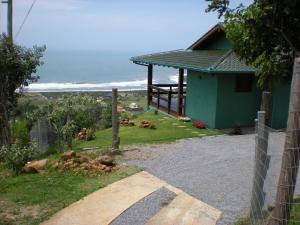 uma casa ao lado de uma estrada com o oceano em Panorâmica Praia da Silveira em Garopaba