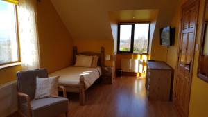 a bedroom with a bed and a chair and windows at Leroy´s Lodge in Headford