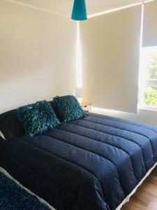 a bed in a bedroom with a blue blanket at Lomas de Papudo 3, Bosque y Playa in Papudo