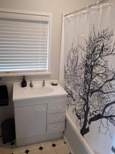 a bathroom with a sink and a shower curtain at Guest house on Plummers Point in Tauranga
