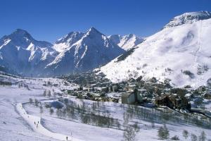uma cidade na neve com montanhas ao fundo em Le Montana em Les Deux Alpes