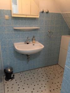 a bathroom with a sink and a blue tiled wall at LORENZ Apartment 2 in Hattingen