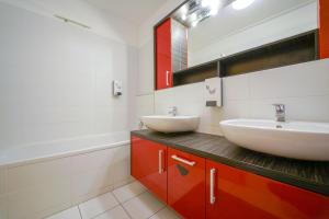 a bathroom with two sinks and a mirror and a tub at Slavic Spacious Apartment in Bratislava