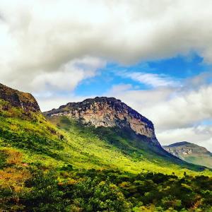 a green hillside with a mountain in the background at Do Alto da Montanha Pousada in Vale do Capao