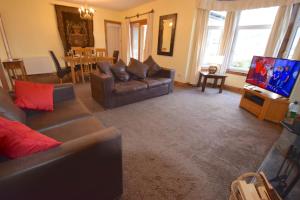 a living room with a couch and a television at Ashburn Cottage in Lochgoilhead