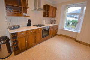 Una cocina con armarios de madera y una ventana. en Ashburn Cottage, en Lochgoilhead