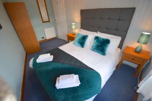 Un dormitorio con una cama grande con dos almohadas azules. en Ashburn Cottage, en Lochgoilhead